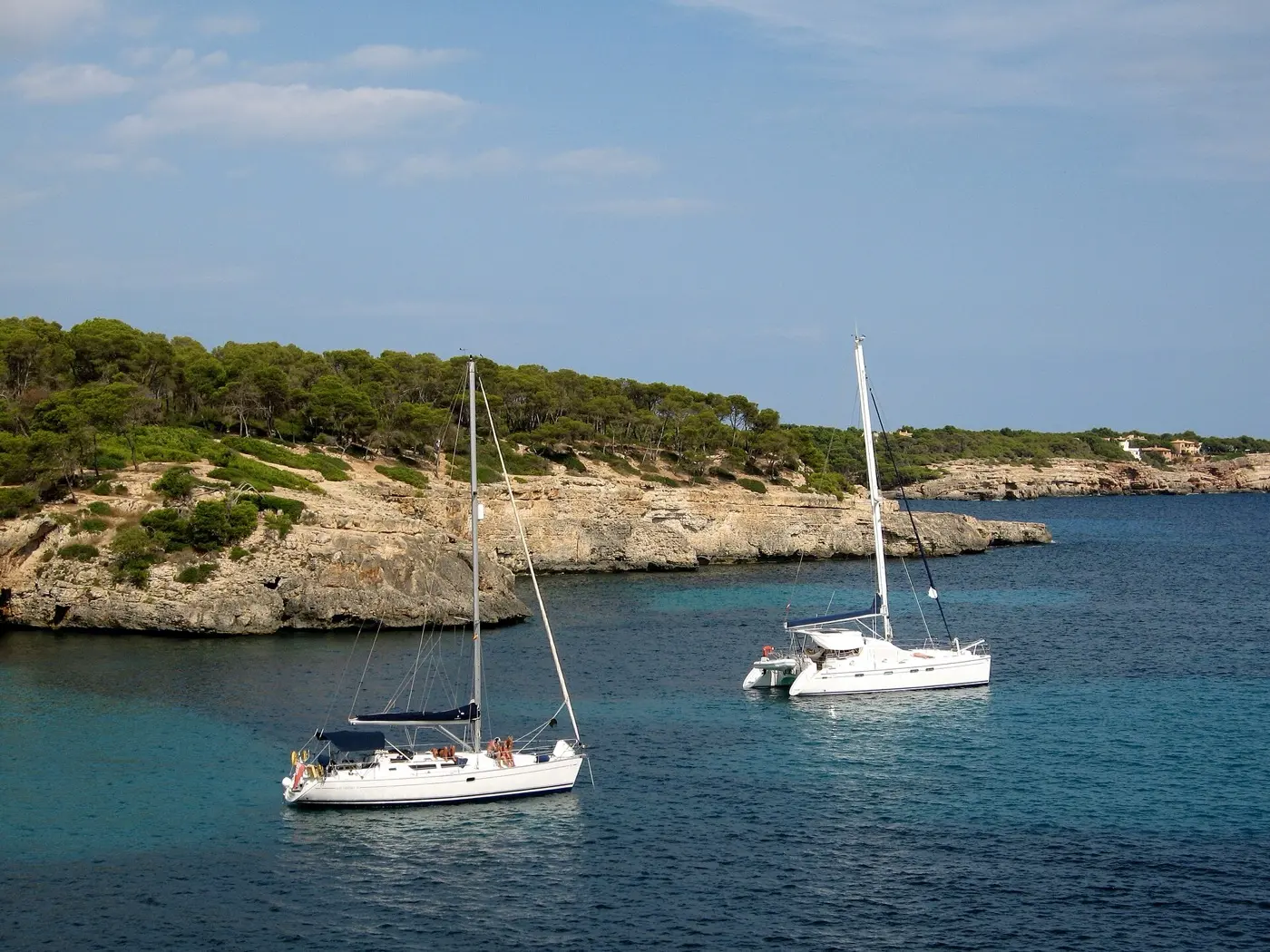 Segelboote in der Bucht Cala Mondragó zwischen felsigen, mit Kiefern bewachsenen Ufern