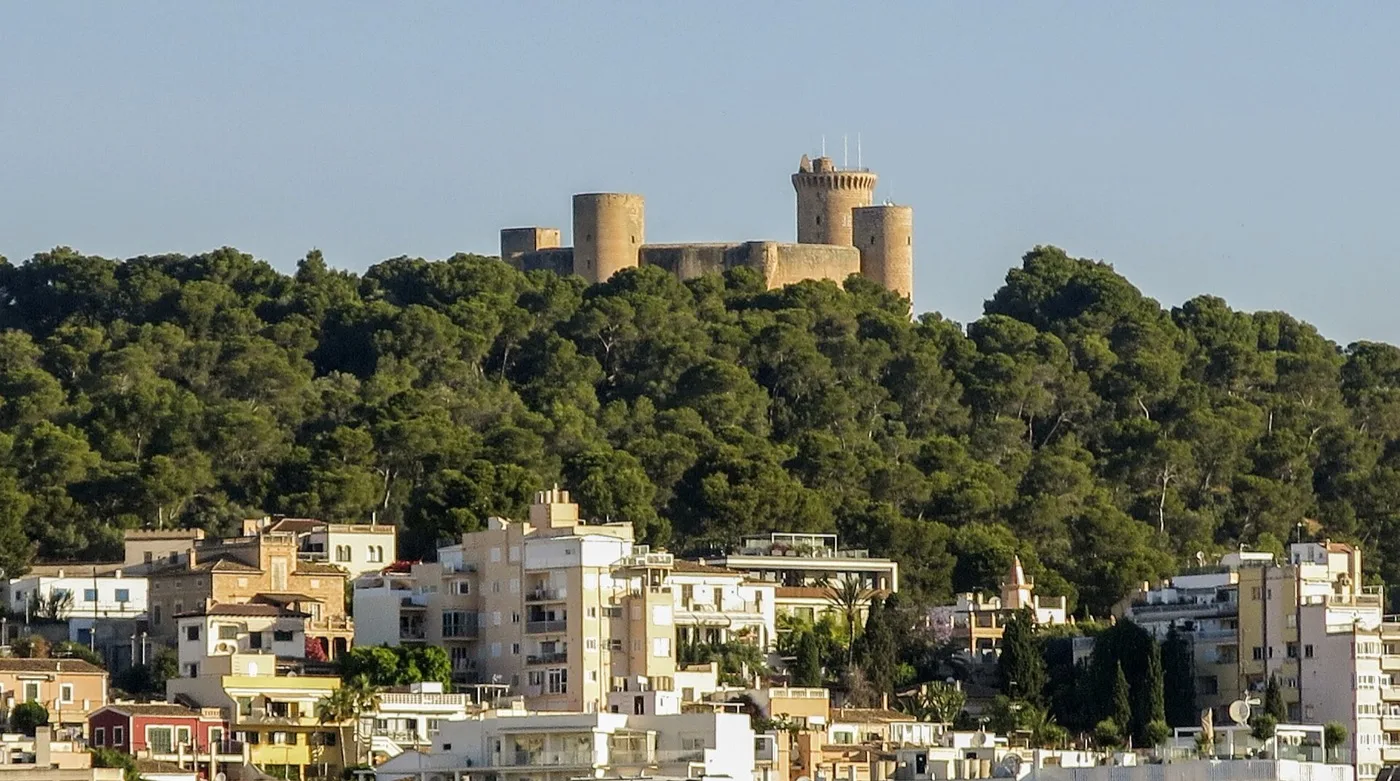 Rundes Castell de Bellver mit Türmen auf einem bewaldeten Hügel über Wohnhäusern