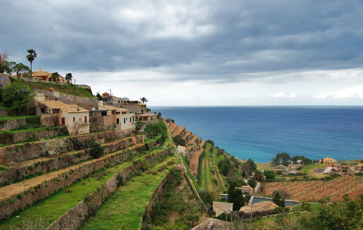 Terrassierte Hänge mit Steinmauern und Häusern über dem Meer in der Serra de Tramuntana