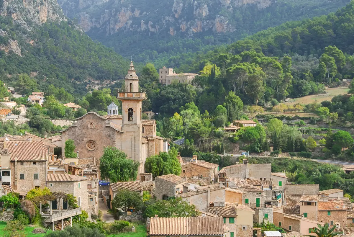 Blick auf Valldemossa mit Kirchturm, Steinhäusern und bewaldeten Bergen